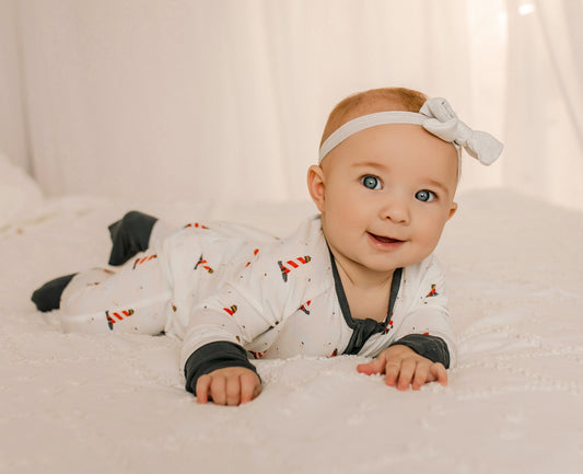Baby wearing a white onesie with black, red, and white lighthouse pattern