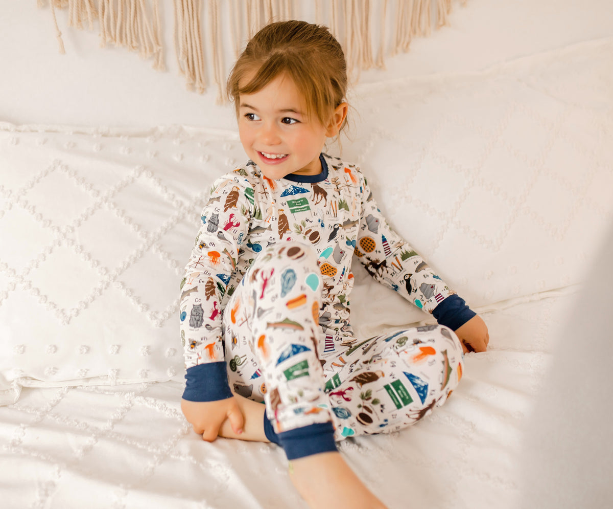 Child wearing pajamas with a pattern of animals, lobsters, fish, and more that all represent Maine for every letter of the alphabet