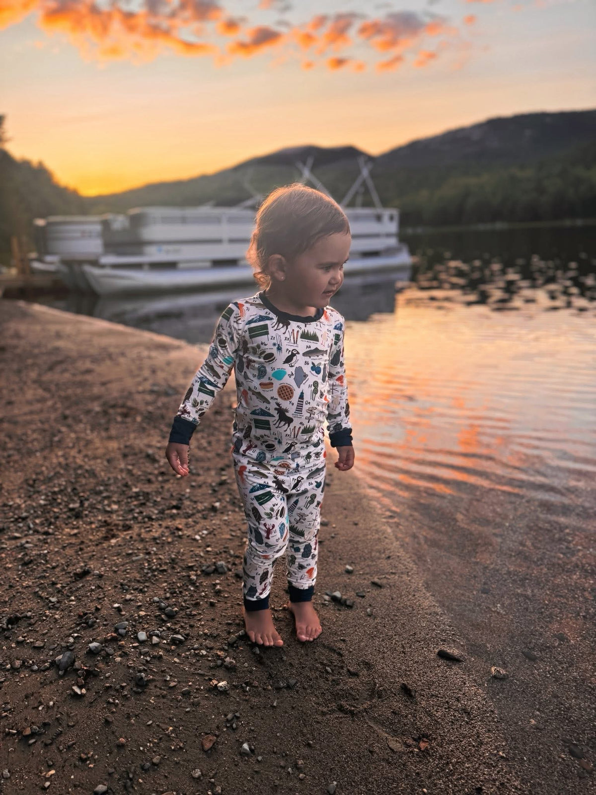 Child wearing a white background with all kinds of items from lobsters and blueberries to waffles and eagles, to each represent a letter of the alphabet