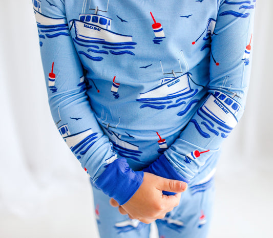 Blue children's pajamas with Maine lobster boats, red white and blue buoys, seagulls flying, and waves under the boats