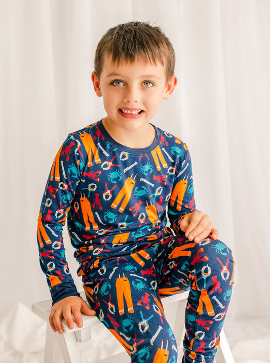Child wearing a colorful pajama set with lobsters, crabs, and all the essentials for working on a lobster boat
