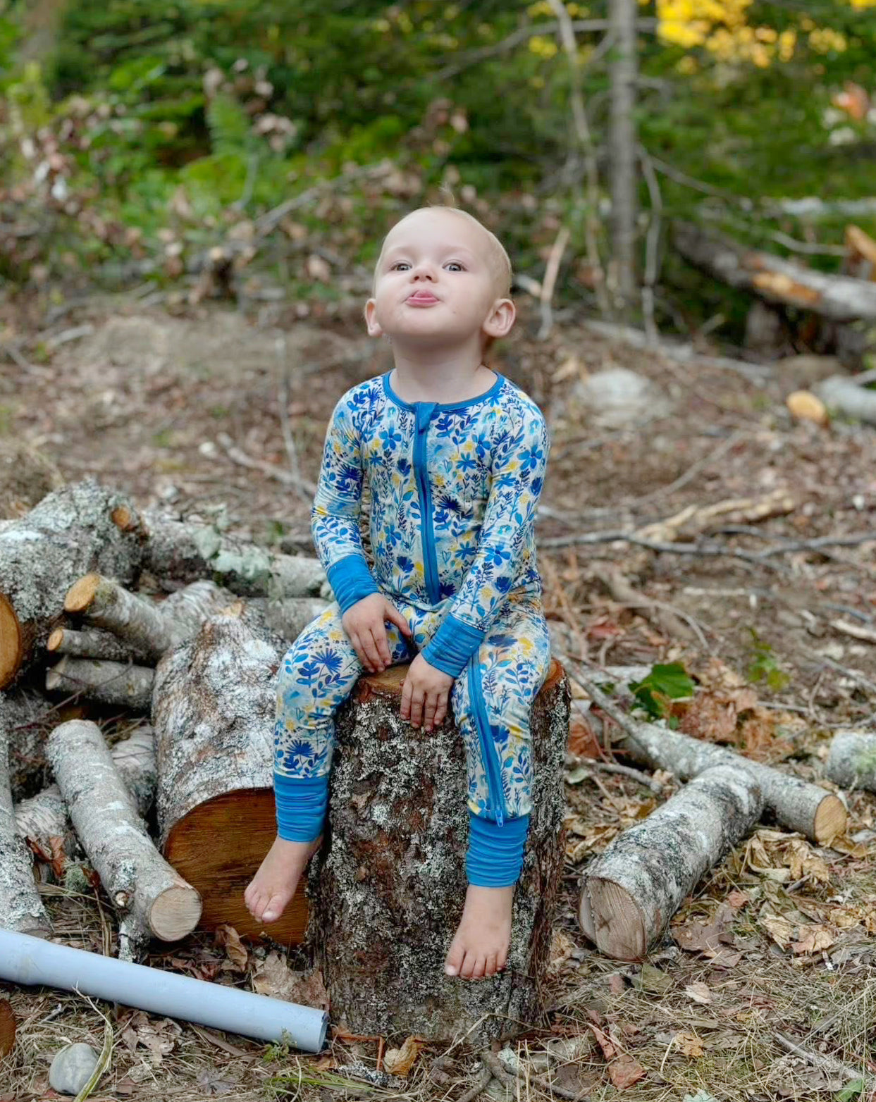 Child in a colorful blue, yellow, and white floral onesie of the Maine wildflowers with light blue cuffs