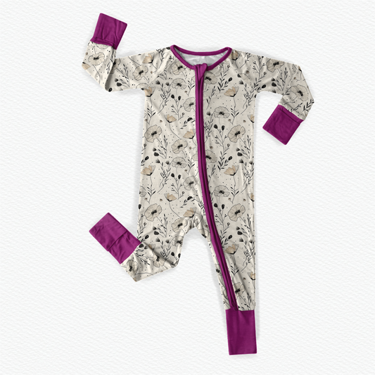 Baby one piece with floral pattern of the poppy flower on a off white colored background and purple accents 