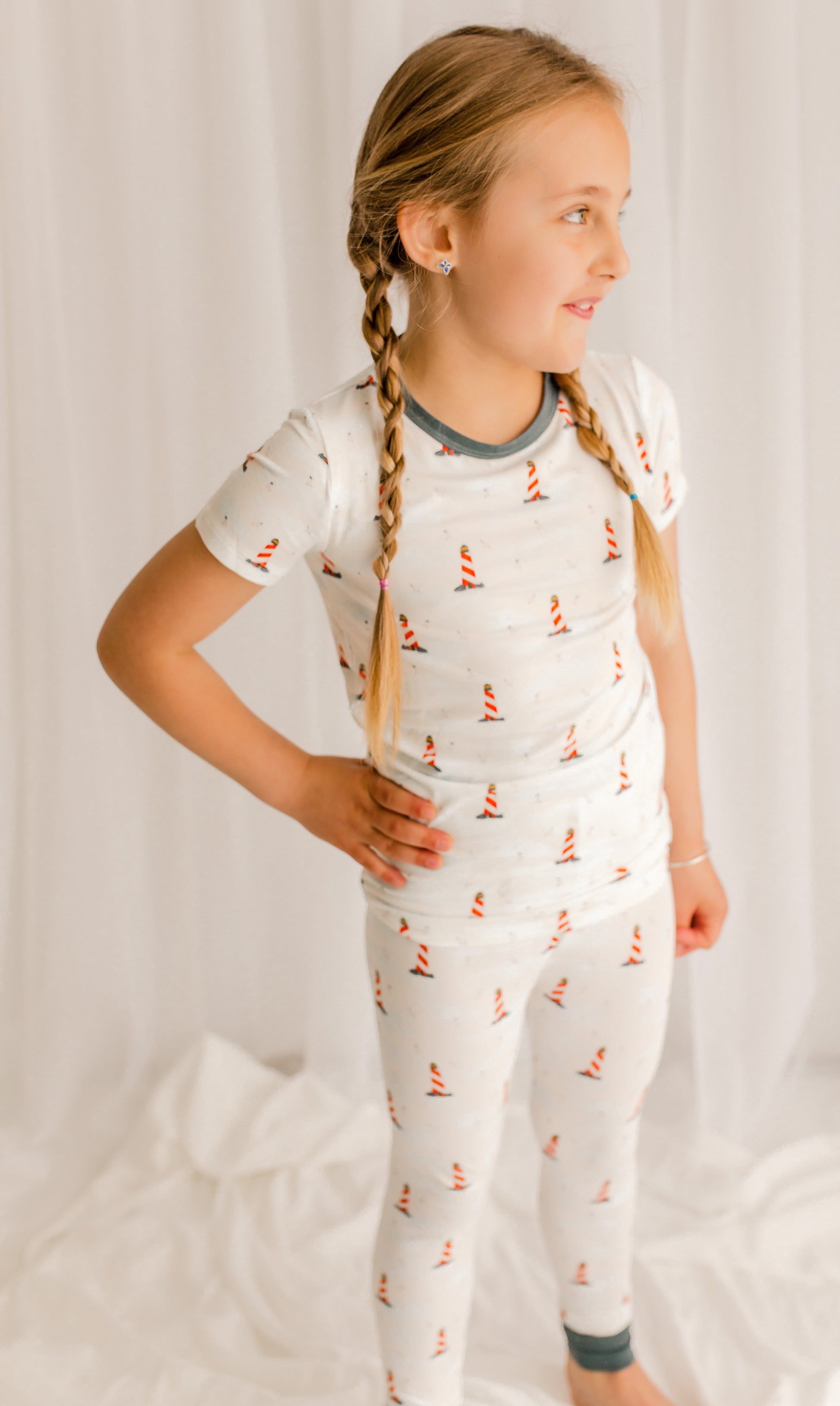 Young girl wearing a white pajama set with  Maine lighthouse 