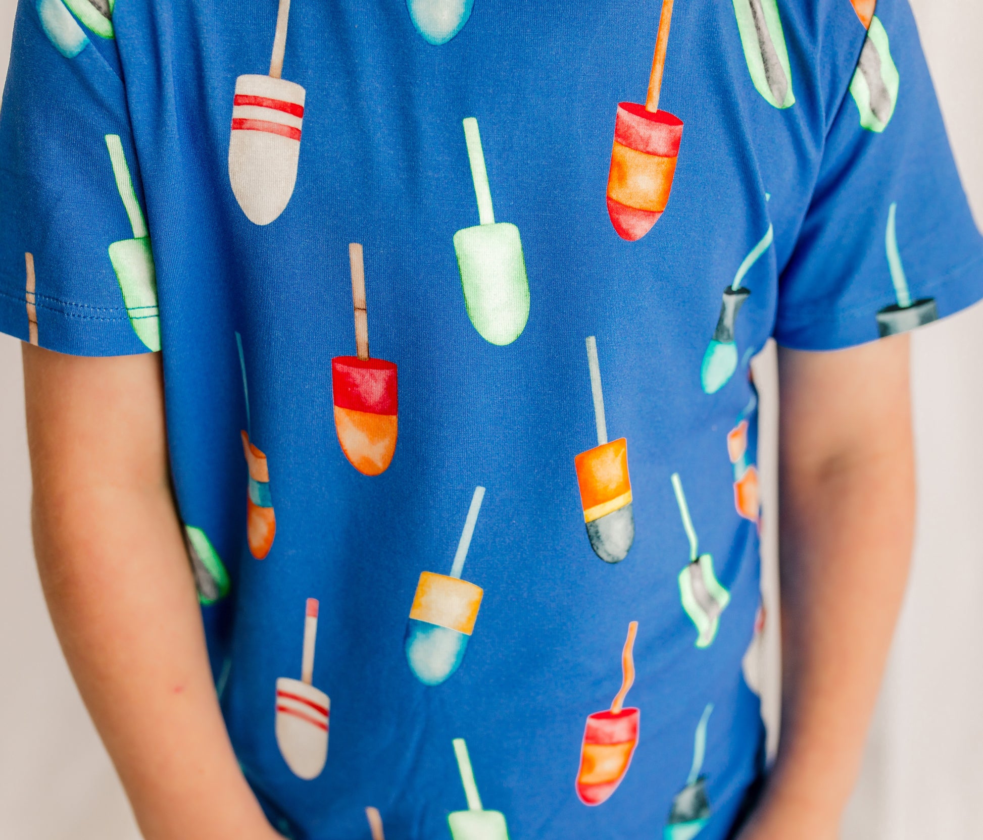 Child wearing a blue pajama set with colorful buoys all over 