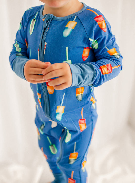 Child wearing a blue pajama set with colorful buoys all over 