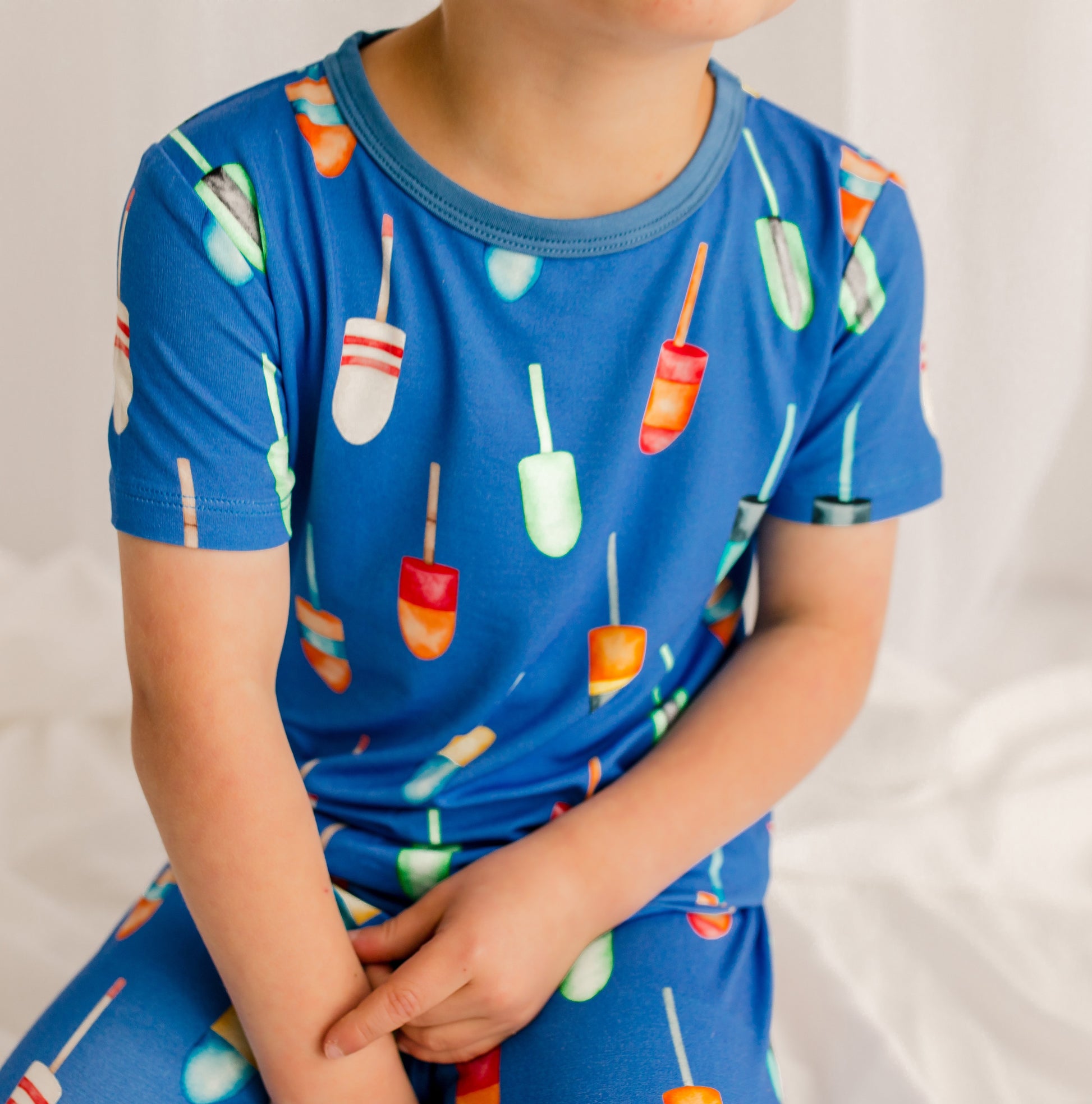 Child wearing a blue pajama set with all kinds of buoys with different patterns and colors 