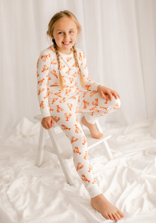Young girl wearing white pajamas with the Maine orange lobster patterns all over 