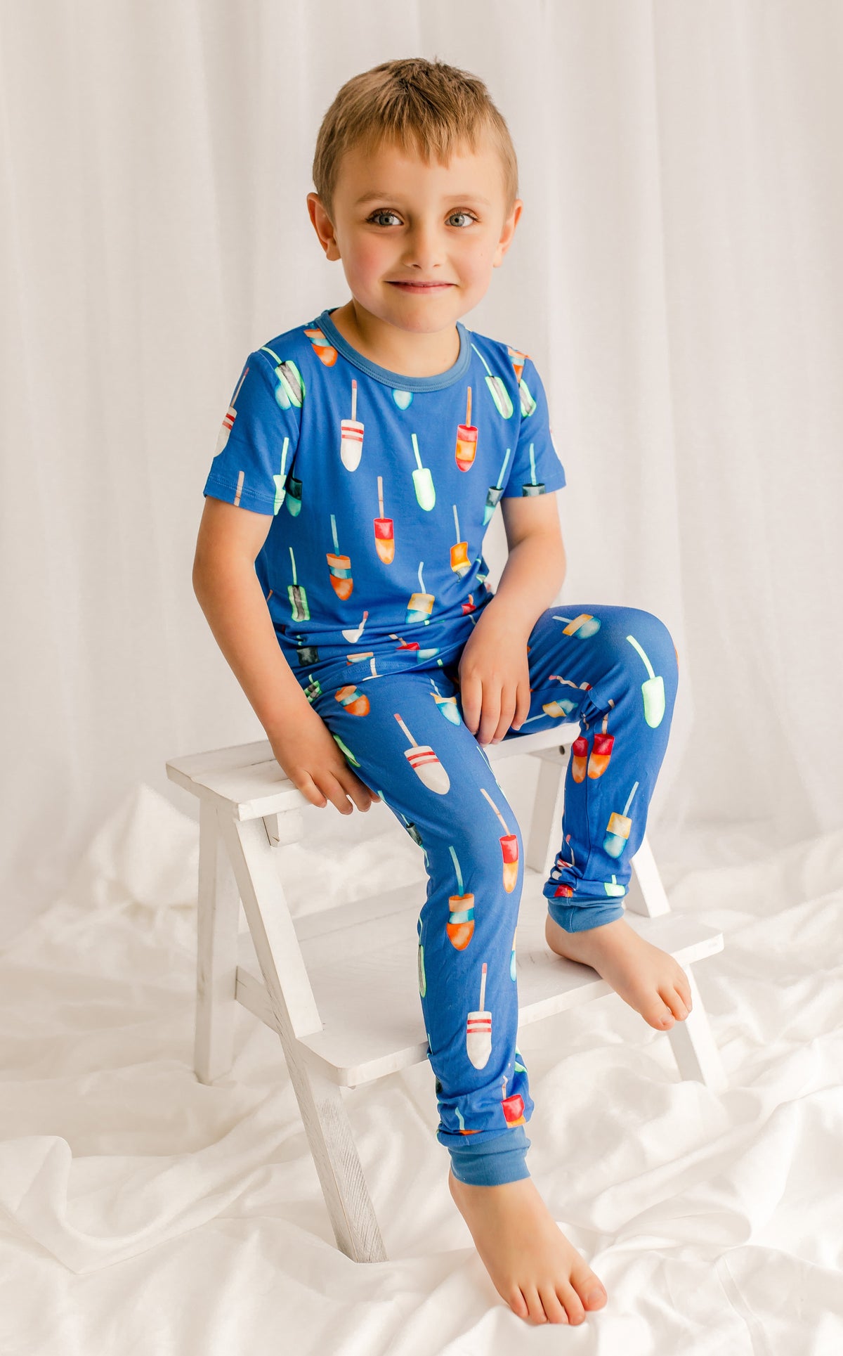 Child wearing blue pajamas with all different pattern buoys that are used in lobster fishing in Maine 