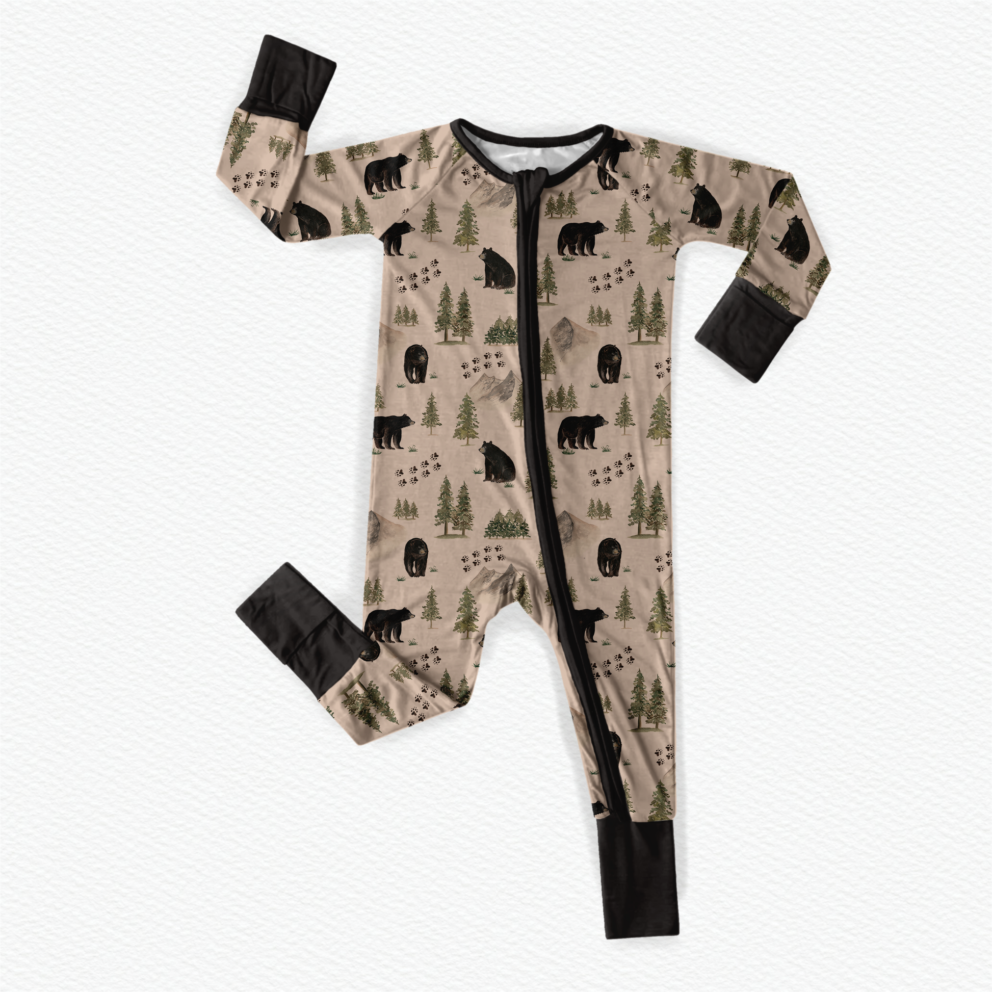 Baby onesie with bear and forest patterns along with animal tracks on a tan background with black accents 