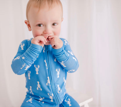 A blue long-sleeved baby onesie with a pattern of white lobsters on a blue background with blue cuffs 