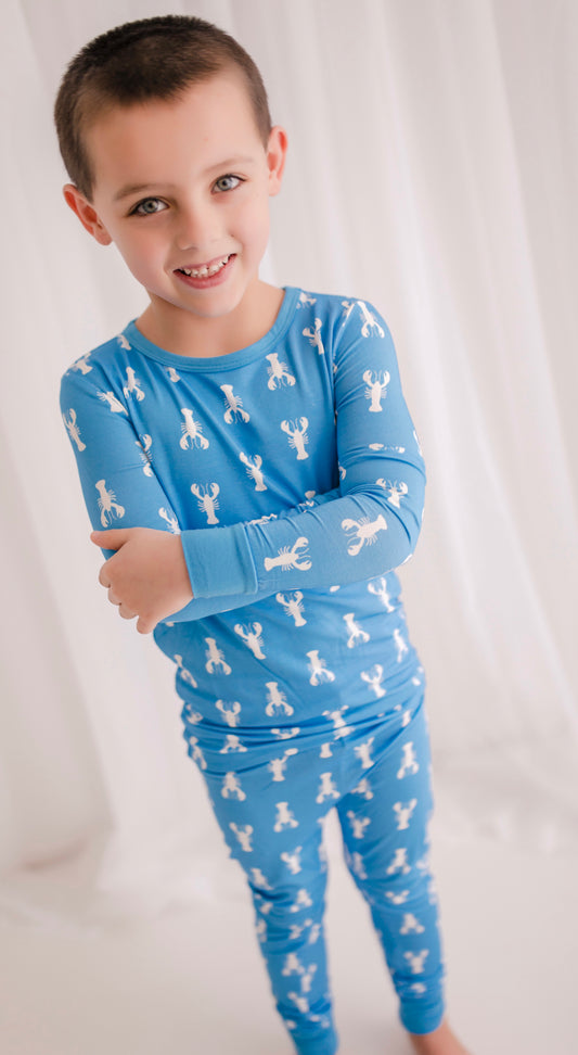 A child wearing a two-piece pajama set with a blue lobster print.