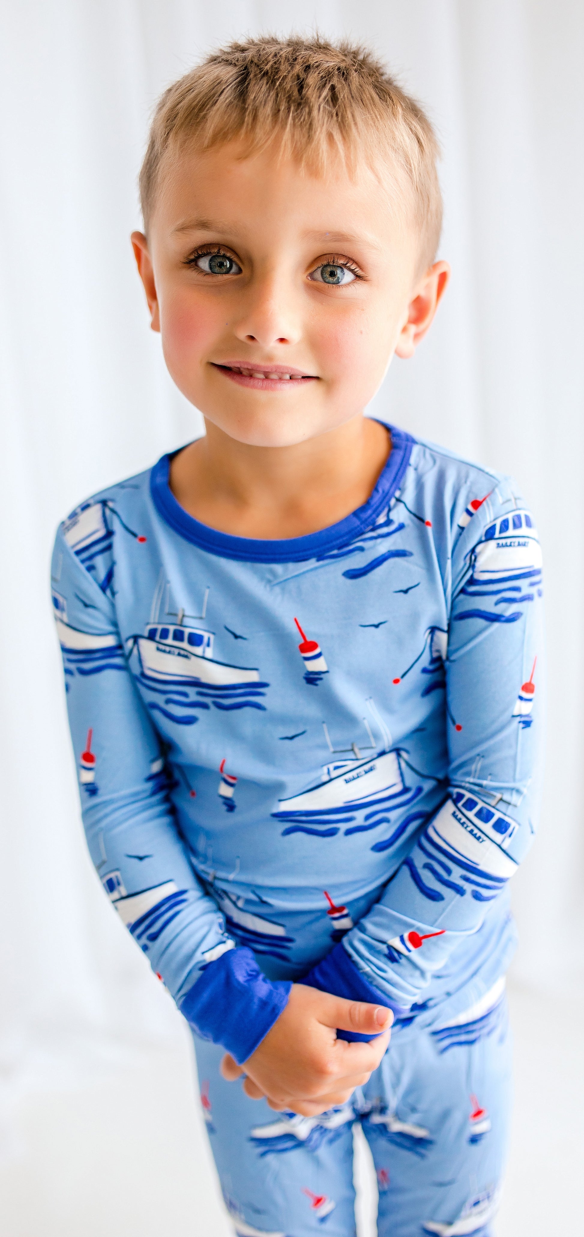 Child wearing light blue pajamas with darker blue accents with Maine fishing boats, buoys, and seagulls 