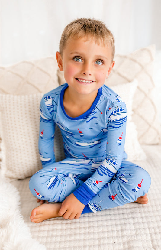Child wearing light blue pajamas with Maine lobster boats with waves, buoys, and seagulls with darker blue accents 