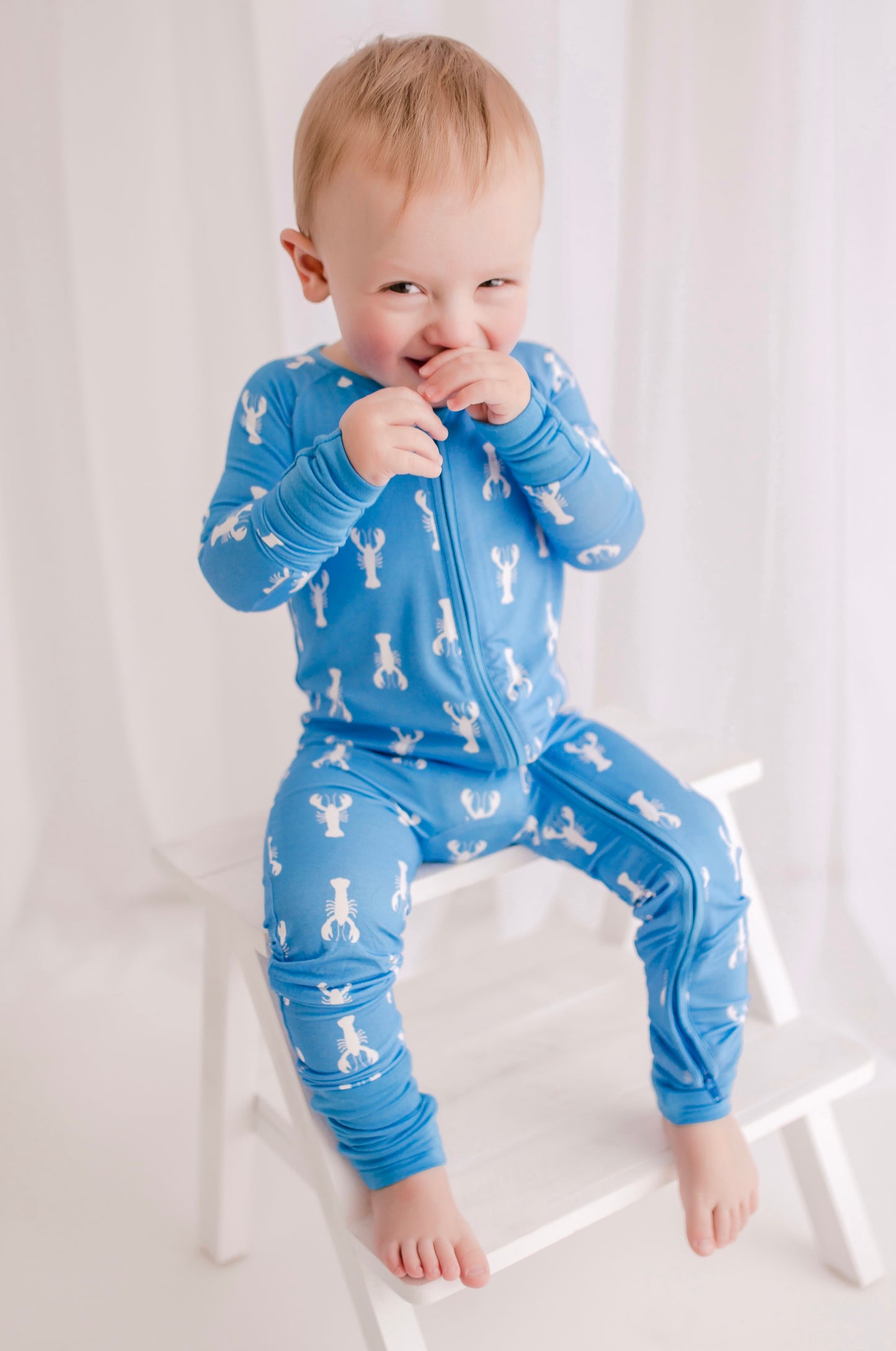 Child wearing light blue zippy with white lobsters and blue cuffs 