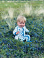 Baby wearing white zippy romper with maine blueberries all over and a darker blue on the cuffs 