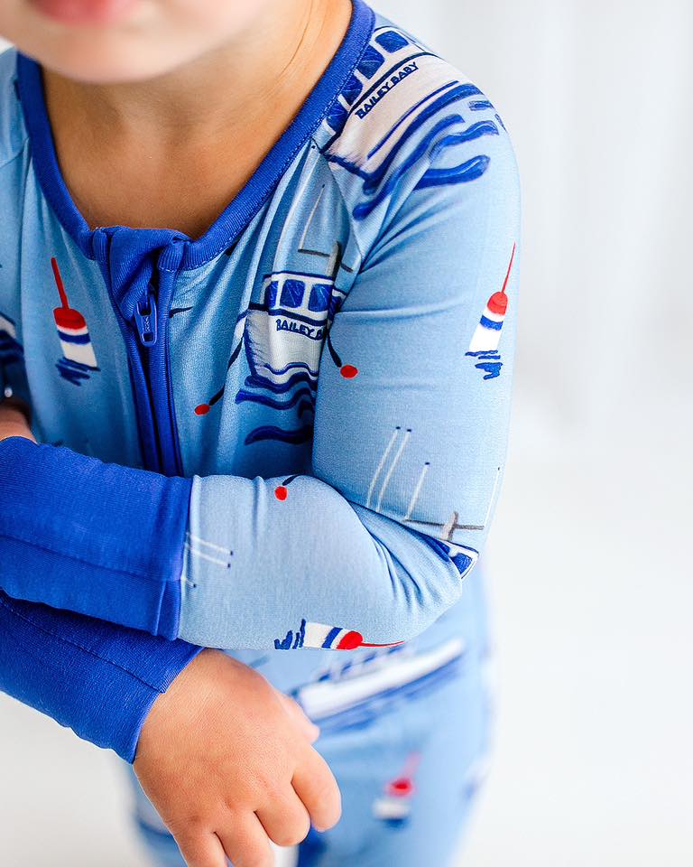 Children's light blue one piece with boats, waves, and buoys set in the atlantic ocean 