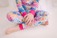 Child wearing colorful two piece pajama set with coral reefs of all different shades of pink, blue, and orange 