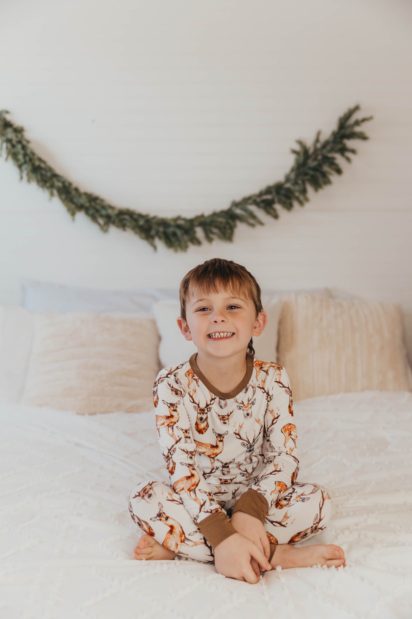 A child wearing a two-piece long sleeved  pajama set with a deer and antlers design