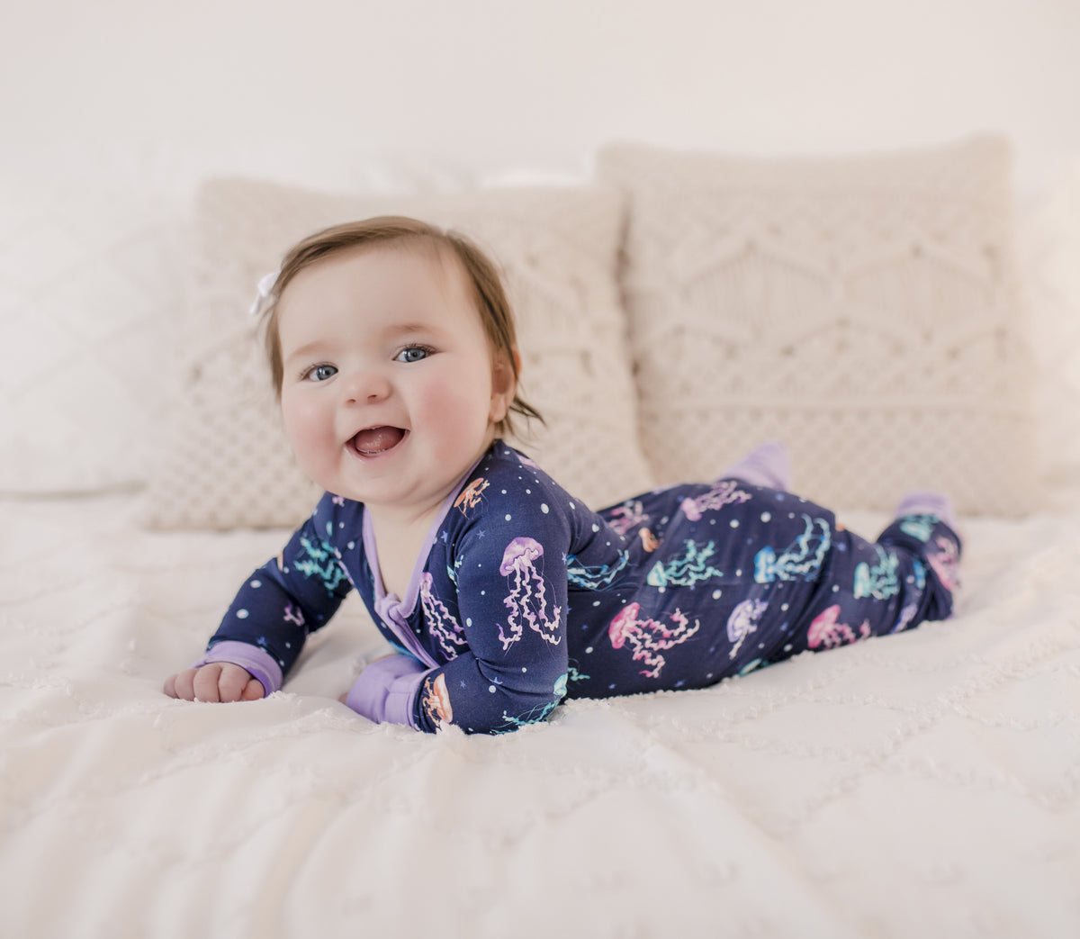 A infant wearing a long-sleeved blue and purple romper with a jellyfish pattern