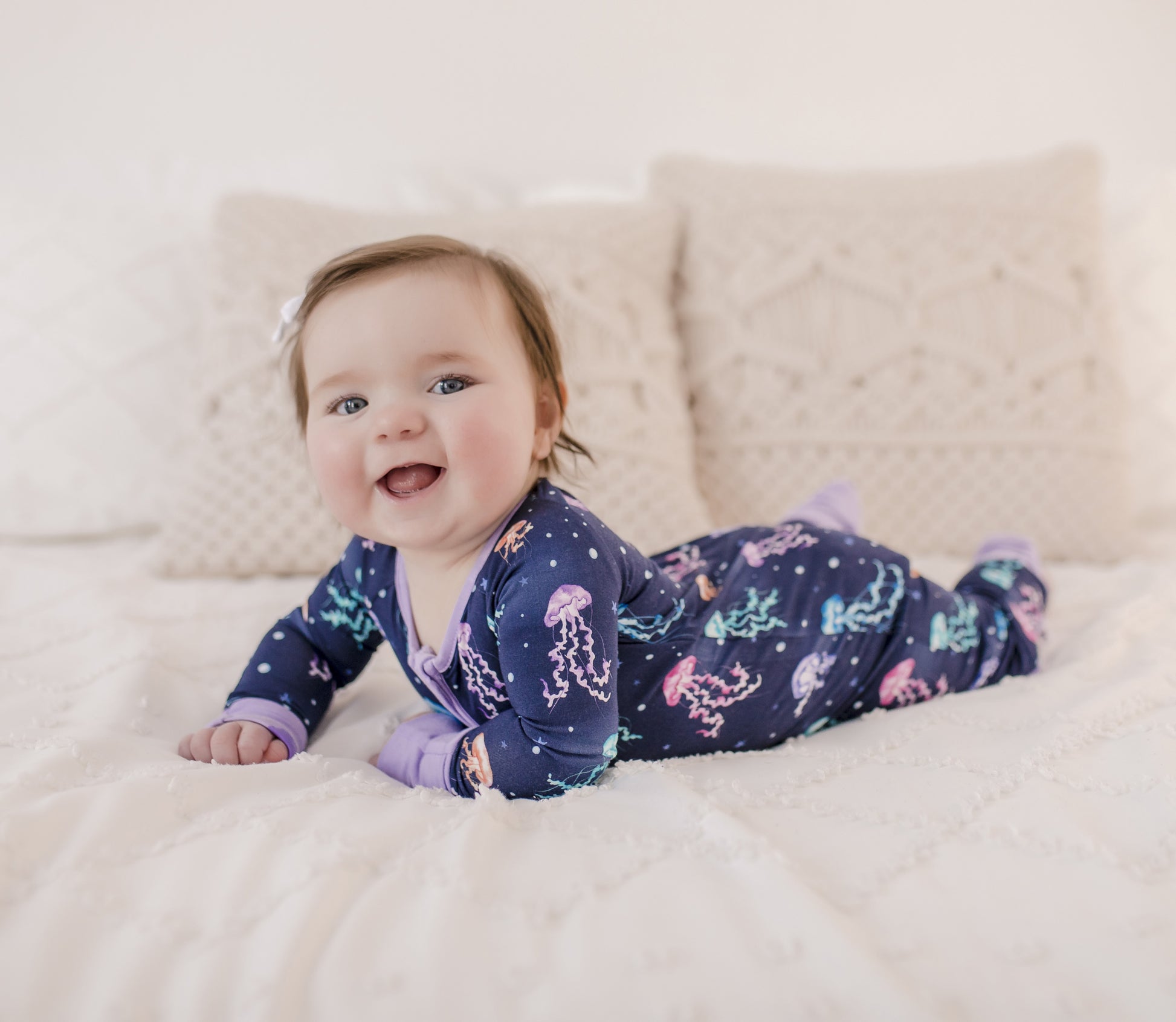 A infant wearing a long-sleeved blue and purple romper with a jellyfish pattern
