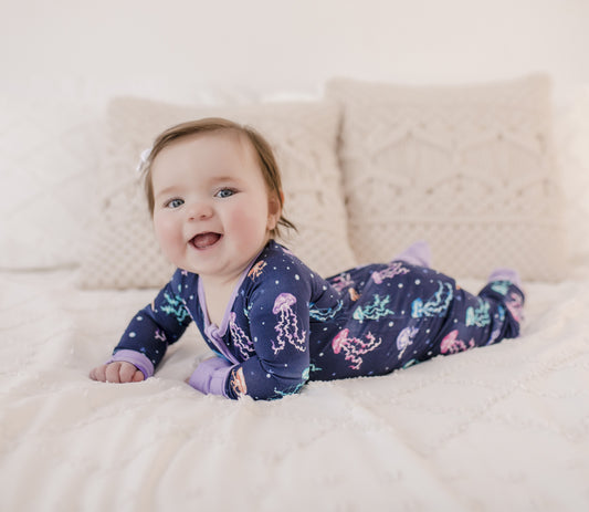 A infant wearing a long-sleeved blue and purple romper with a jellyfish pattern