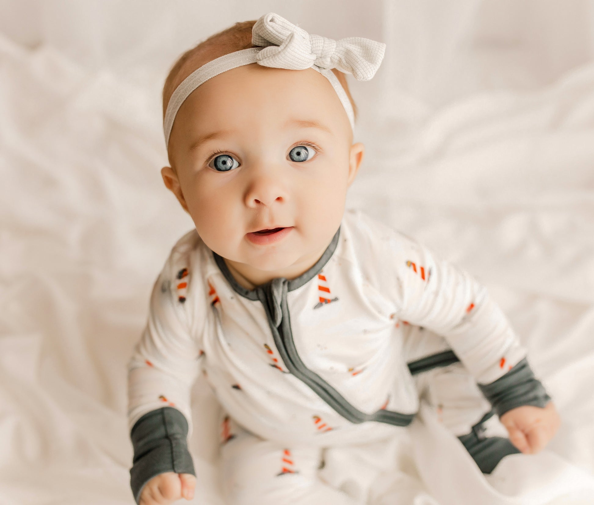 Baby wearing a white one piece with black accents and Maine lighthouses in red and white 