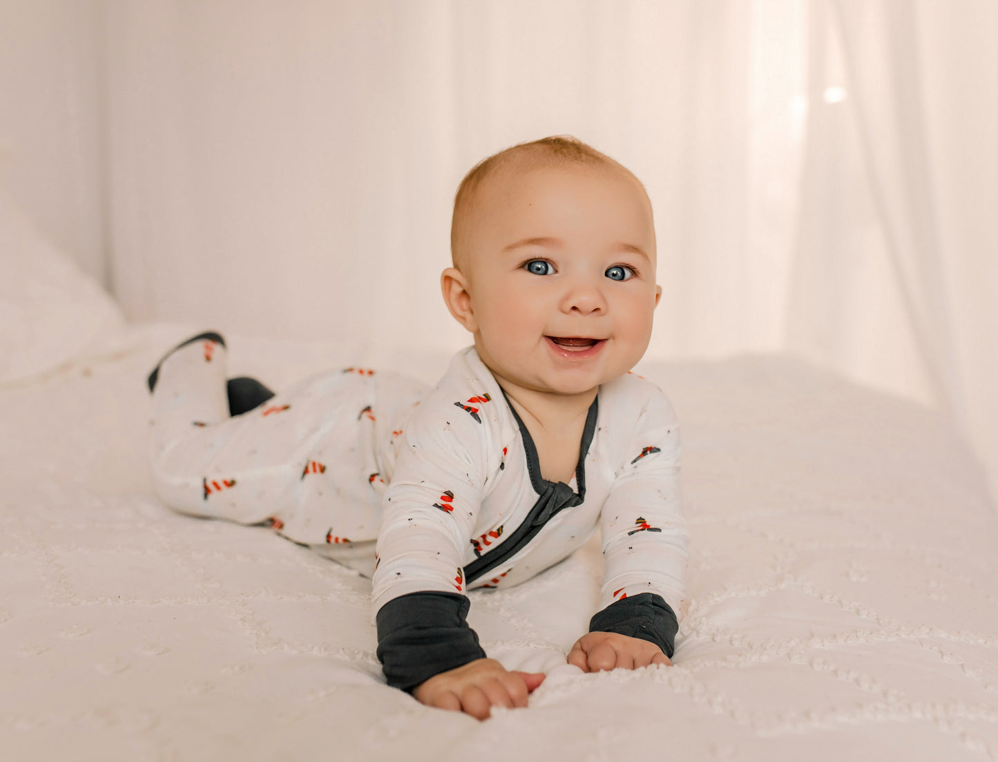 Baby wearing a white one piece with black cuffs and red and white lighthouse  patterns