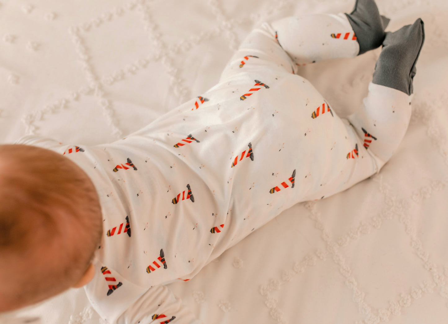 Baby wearing a white onesie with black, red, and white lighthouse pattern 
