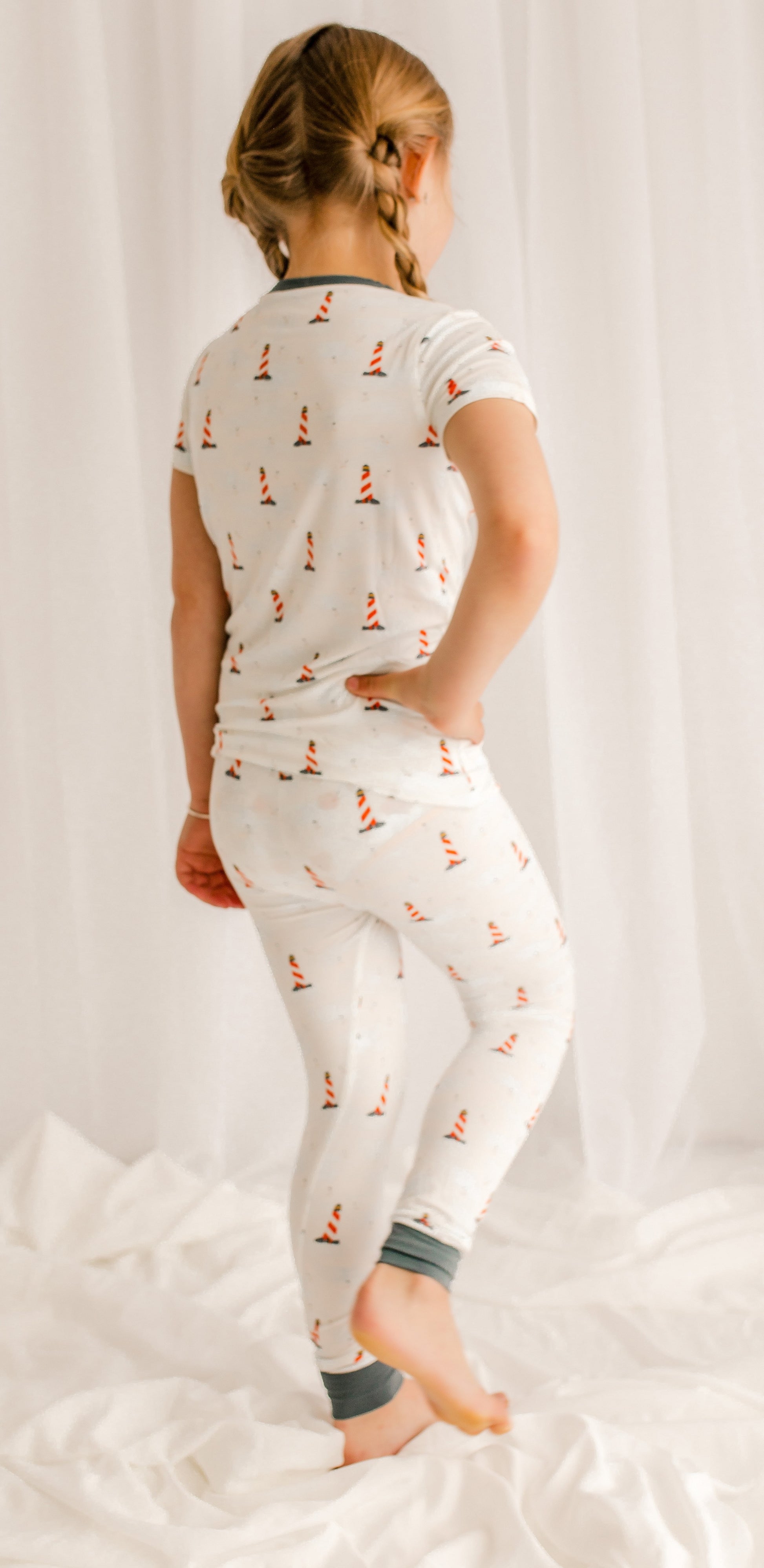 Young girl wearing a white pajama set with  Maine lighthouse 