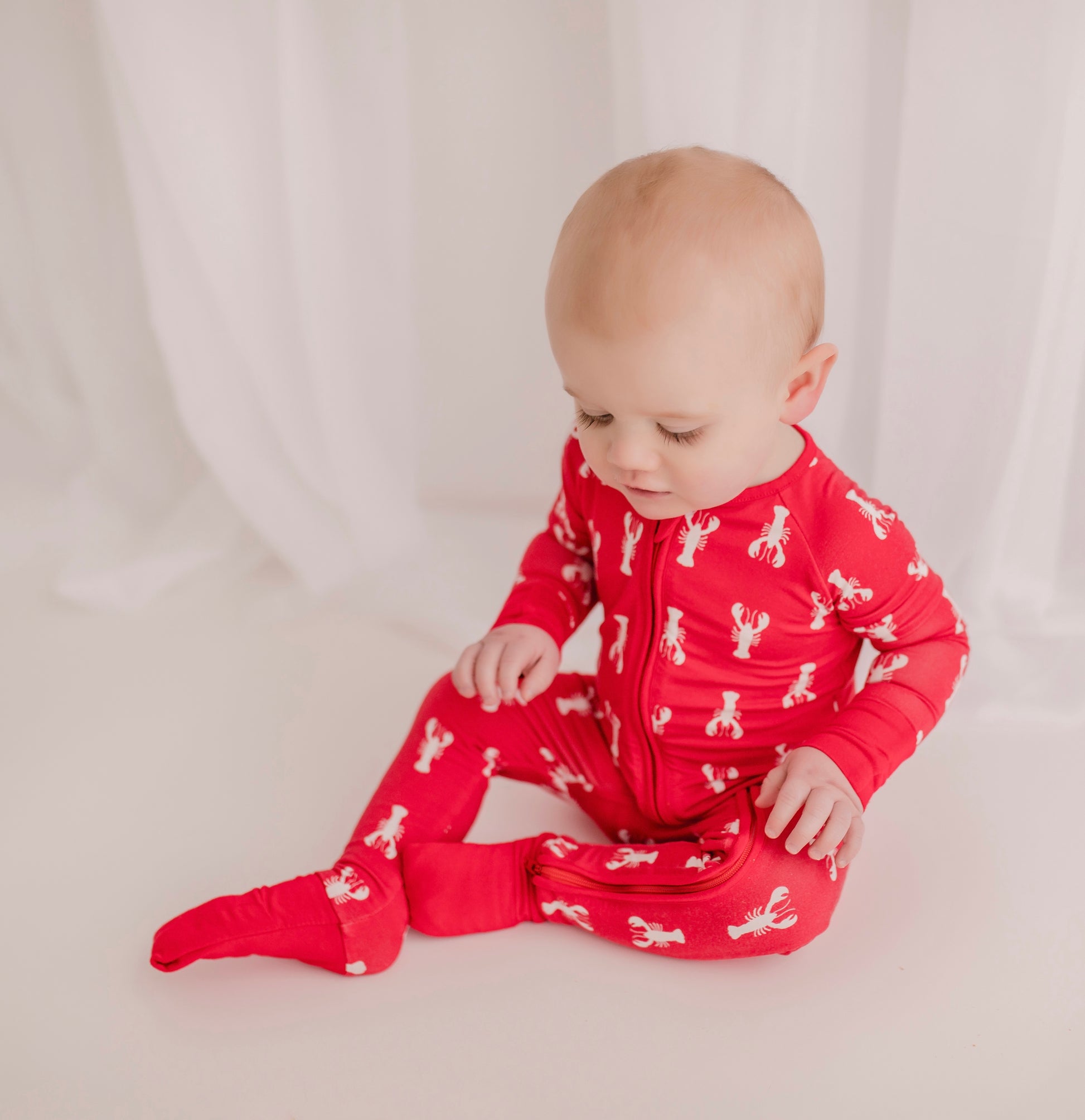 Child wearing white lobster pattern on a red background with red cuffs 