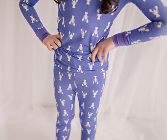 Child wearing a purple long sleeve pajama set with white lobster patterns all over 