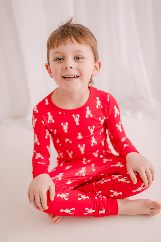 A child wearing red two-piece pajamas with a white lobster design.
