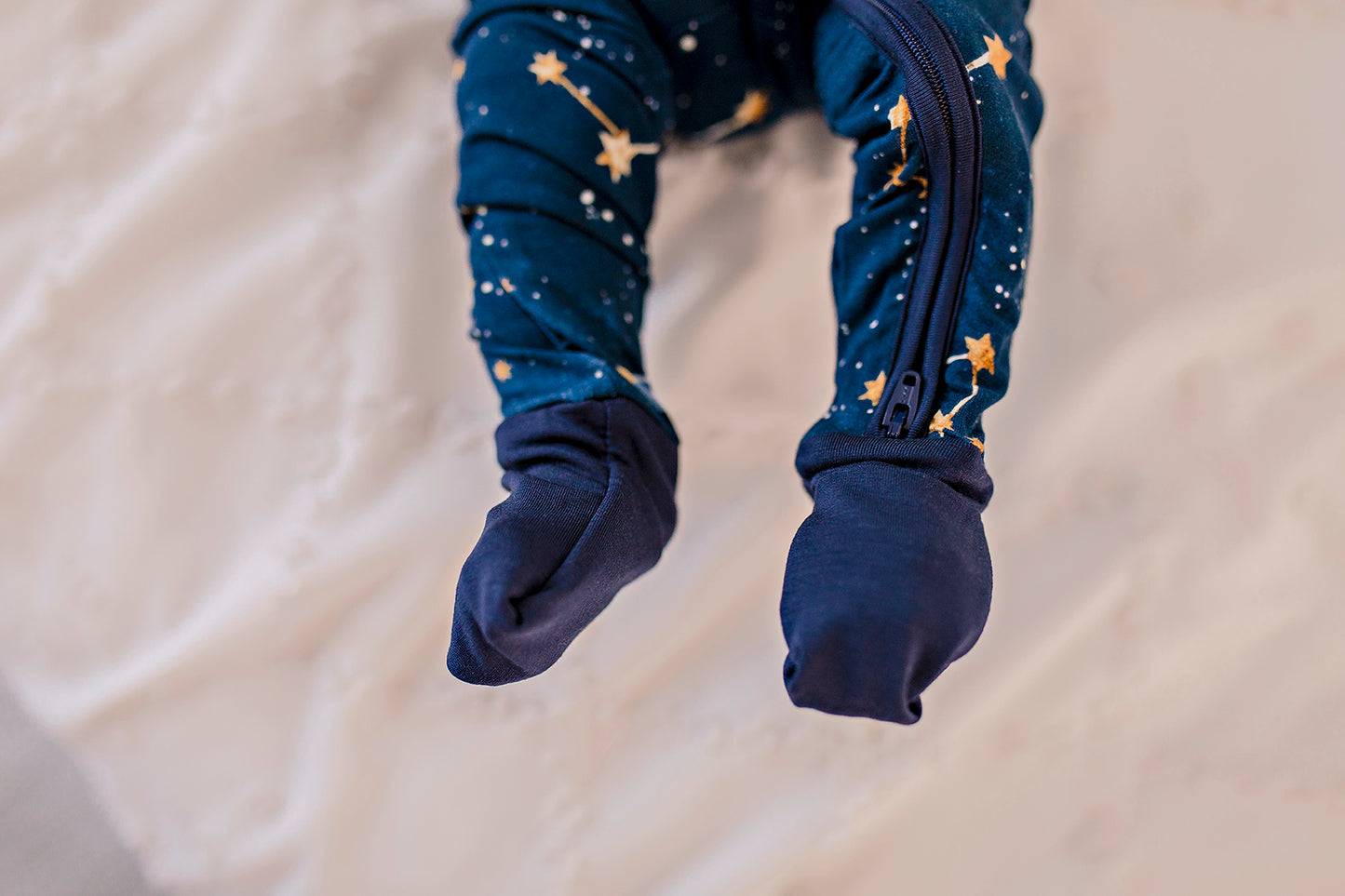 One piece pajamas set with yellow stars, yellow and white constellations, and the galaxy on a dark blue background with blue cuffs 