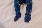 One piece pajamas set with yellow stars, yellow and white constellations, and the galaxy on a dark blue background with blue cuffs 