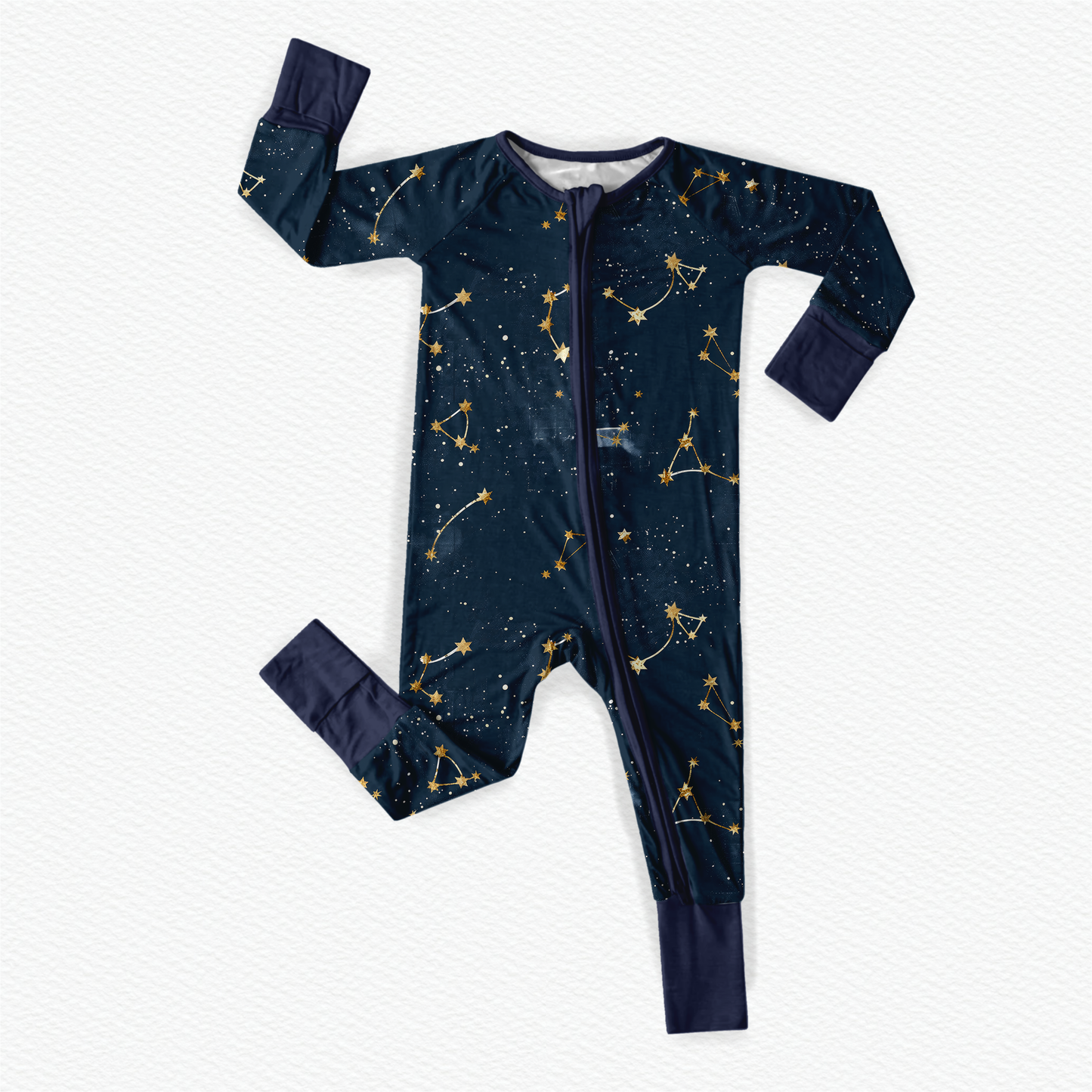 Long sleeved zippy romper with dark blue background with stars, galaxy, and constellations with yellow and white accents throughout and blue cuffs 