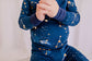 Child wearing a long sleeved dark blue pajama set with the little dipper and big dipper along with the galaxy and stars 