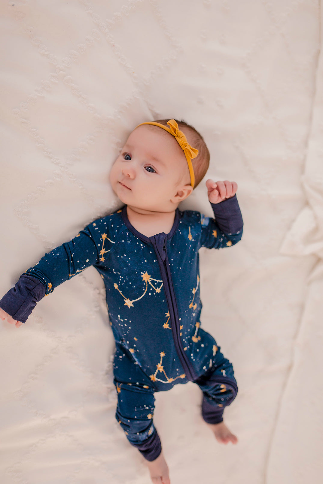 A dark blue long sleeved zippy with the galaxy, stars, and constellations with dark blue cuffs 