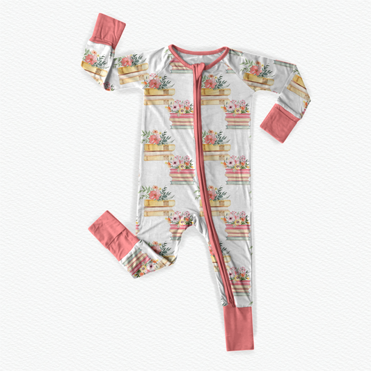 Floral patterned baby onesie with pink accents and colorful books on a white background