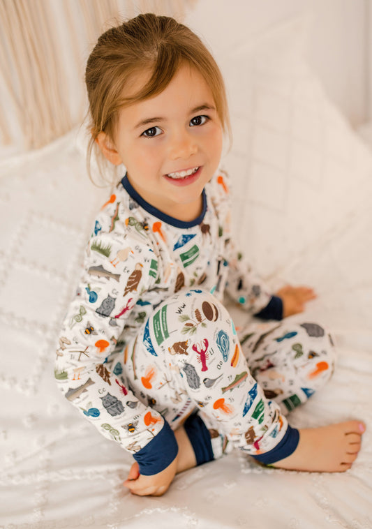 Child wearing pajamas with a pattern of animals, lobsters, fish, and more that all represent Maine for every letter of the alphabet 