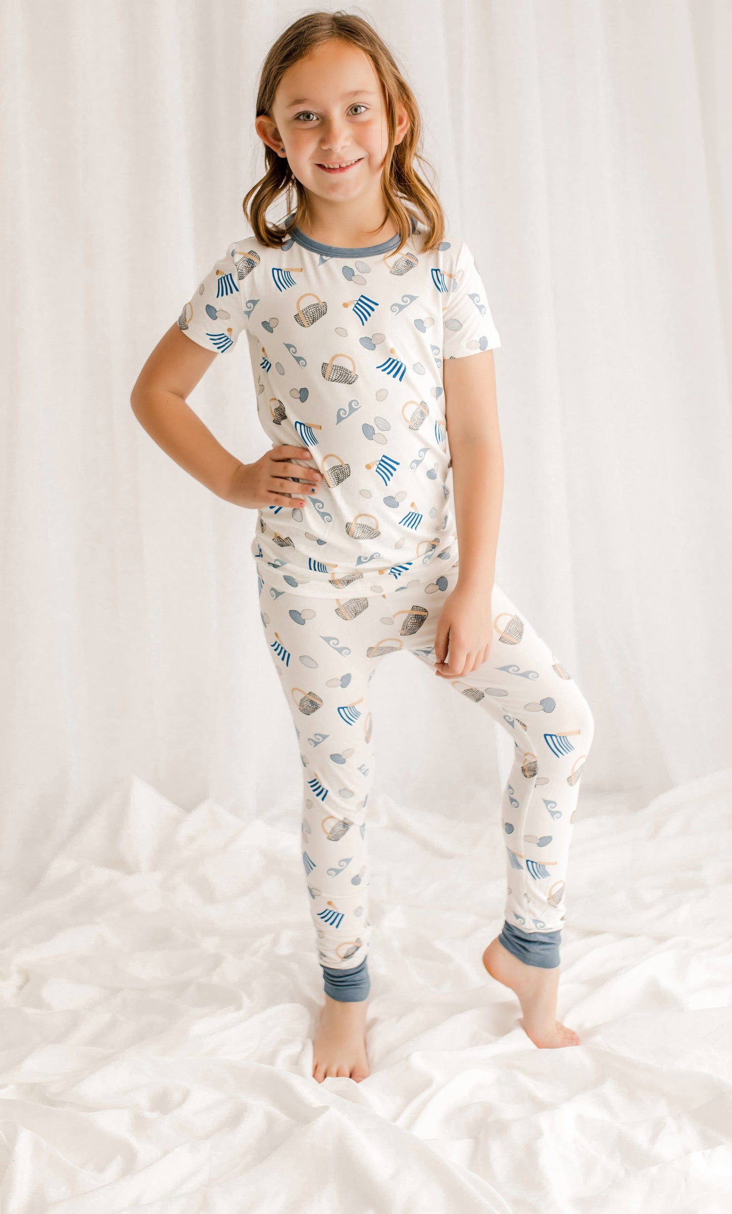 Child wearing a pajama set with clamming patterns on a white background