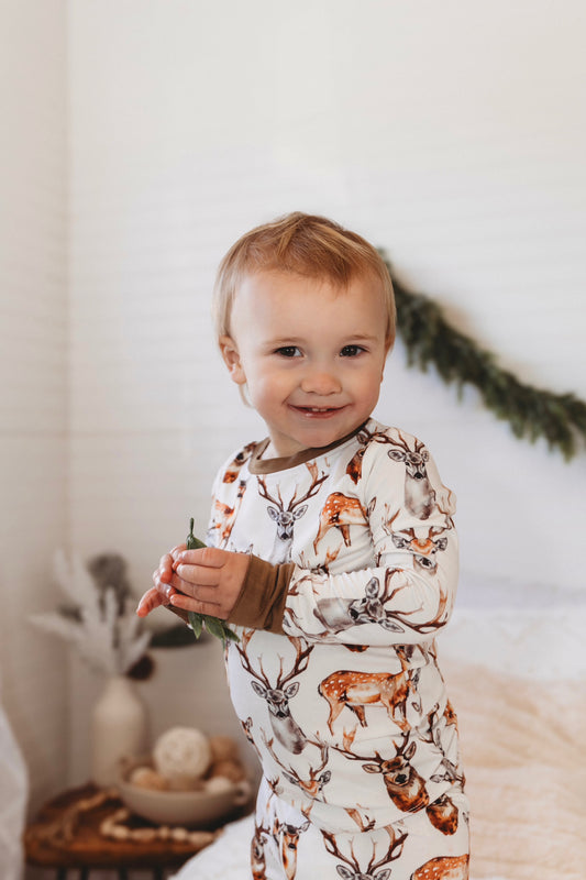 Child wearing pajamas with maine deer on a white background with brown accents 