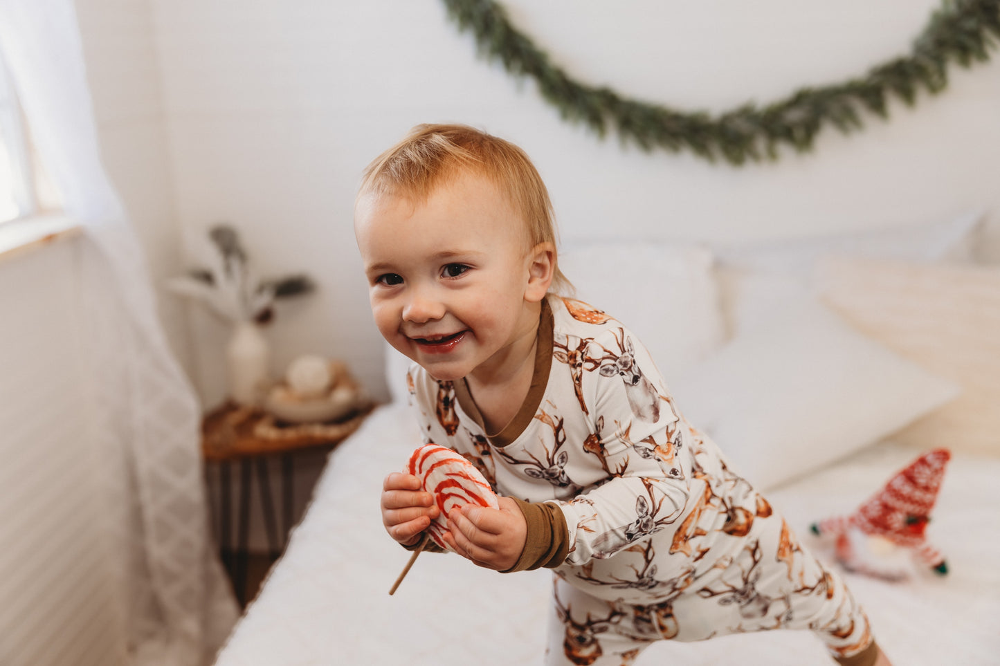Child in pajamas with different colored brown deer with horns on a white background with brown cuffs 