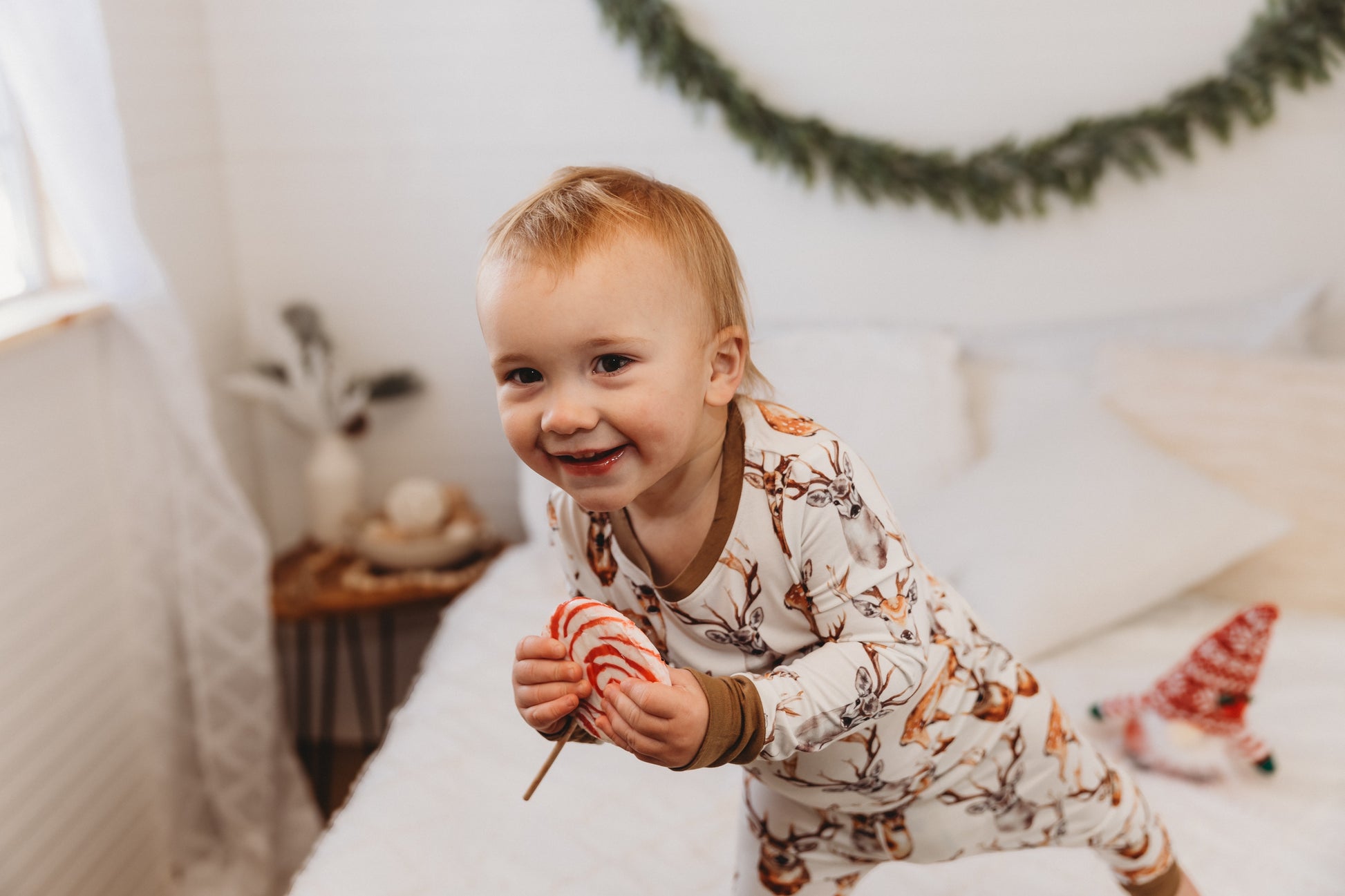Child in pajamas with different colored brown deer with horns on a white background with brown cuffs 