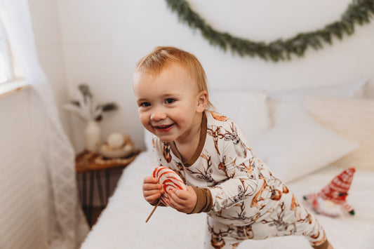 Child in pajamas with different colored brown deer with horns on a white background with brown cuffs 