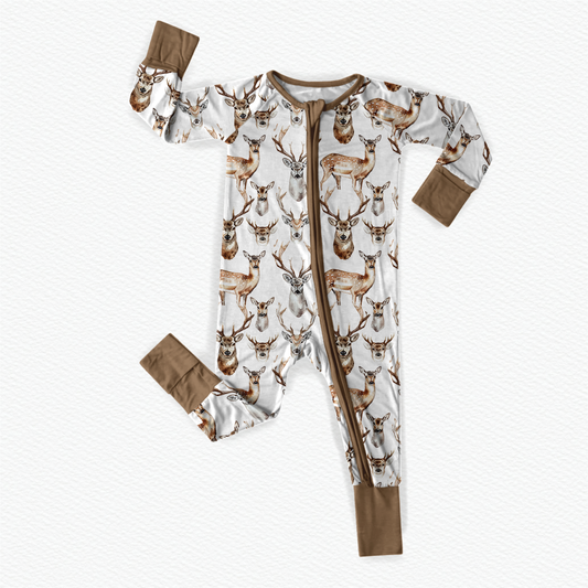 Long sleeved one piece pajama that has deer with antlers on a white background with brown cuffs 