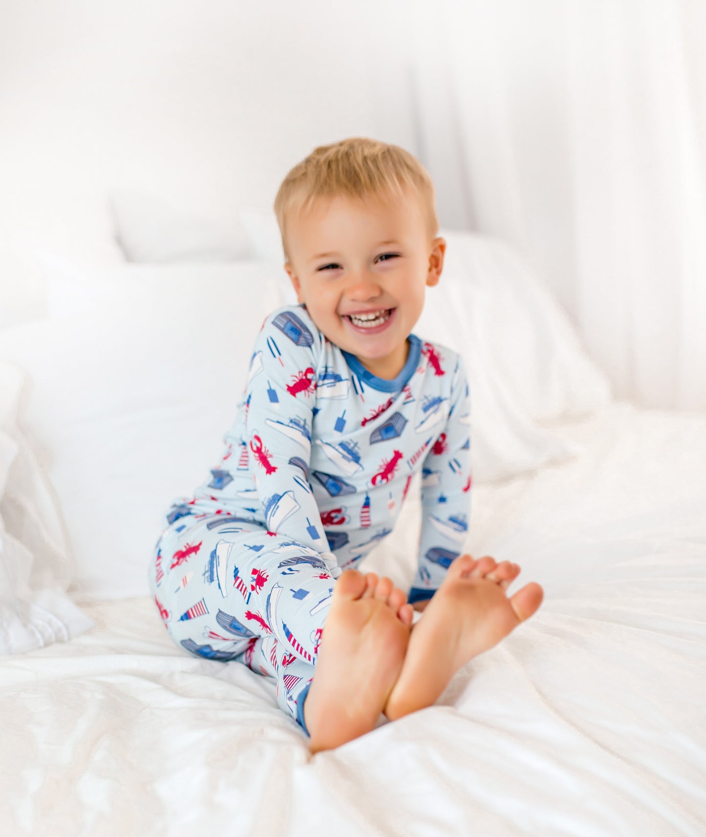 Maine-inspired coastal print featuring red lobsters, lobster boats, buoys, and lighthouses on a soft light blue background