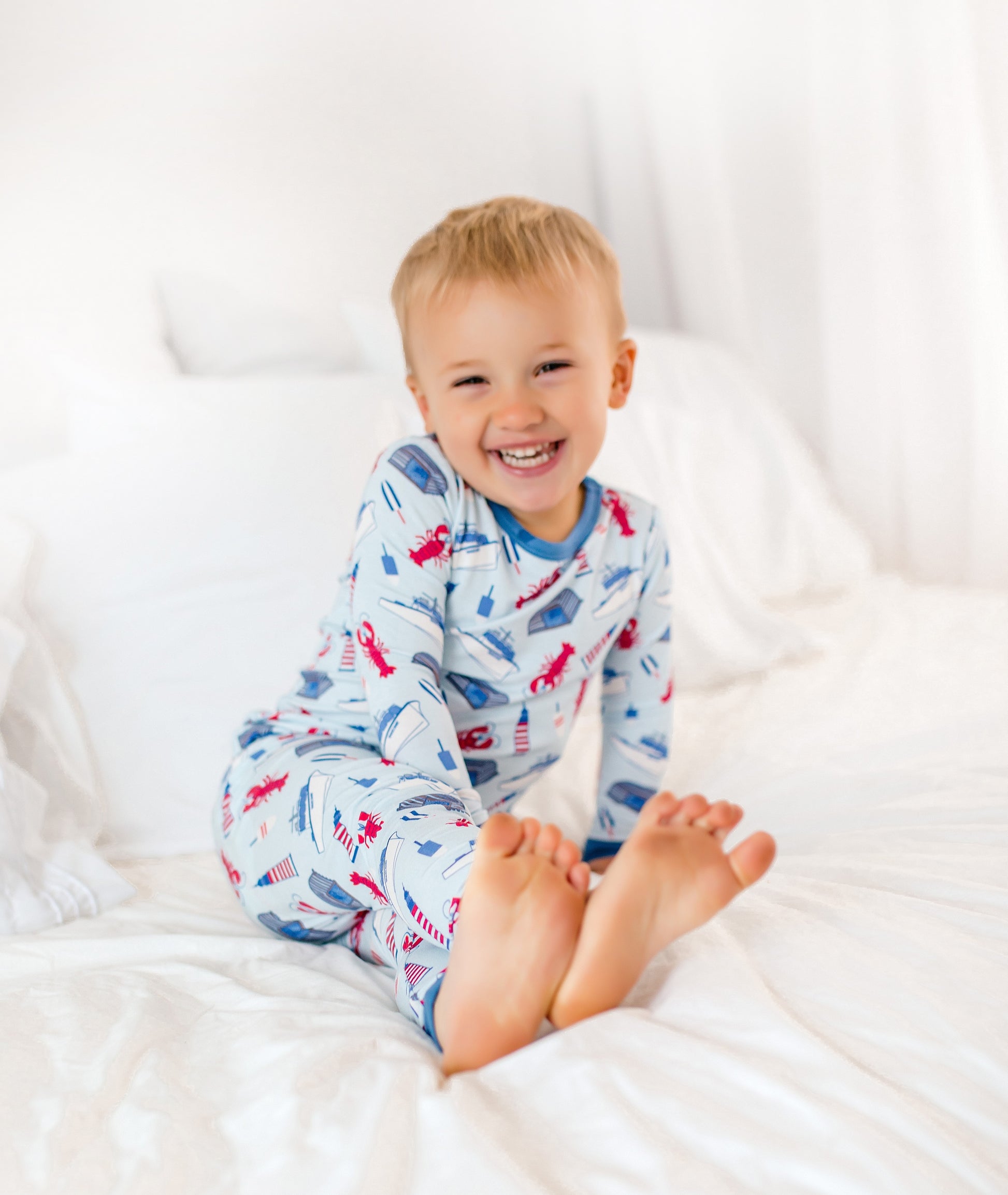 Maine-inspired coastal print featuring red lobsters, lobster boats, buoys, and lighthouses on a soft light blue background
