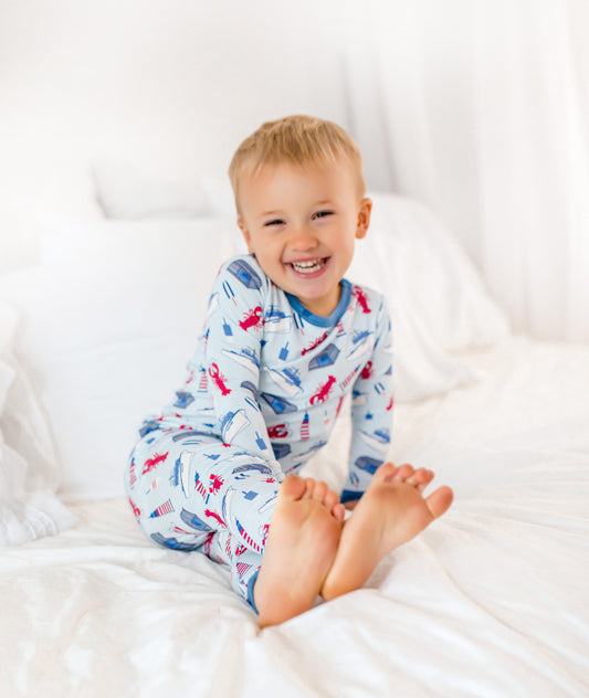 Maine-inspired coastal print featuring red lobsters, lobster boats, buoys, and lighthouses on a soft light blue background