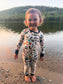 Child wearing an alphabet themed one piece pajama about all the things that represent maine, like puffins, moose, blueberries, eagles, and lobsters on a white background with blue cuffs. 